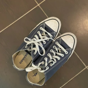 Mörkblå Converse All Star sneakers - Klassiska mörkblå Converse All Star sneakers med vita snören och gummitå. Skorna har lågt skaft, vit sula och tydlig logga baktill. Något slitet tyg i hälen, annars fräscha! 