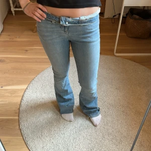 Ljusblå bootcut jeans - Säljer ett par ljusblå jeans med bootcut passform och låg midja. Jeansen har klassisk femficksdesign, dragkedja och knapp framtill. Perfekta för dig som gillar en retro vibe och vill ha ett par jeans med lite utsvängda ben.