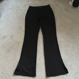 Svarta kostymbyxor från Bik Bok - Snygga svarta kostymbyxor från Bik Bok med bootcut-passform och slits nertill. Byxorna har hällor för bälte och diskreta fickor bak. Perfekta för en stilren look.