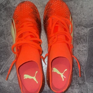 Puma Ultra fotbollsskor i neonorange Pris kan diskuteras!!! - Säljer ett par Puma Ultra fotbollsskor i neonorange med vita detaljer och snörning. Skorna har en lätt ovandel och fasta dobbar för spel på gräs. Perfekta för dig som vill sticka ut på planen!
