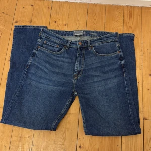 Blå jeans från Dressmann Relaxed Fit - Säljer ett par klassiska blå jeans från Dressmann i modellen Relaxed Fit. Jeansen har fem fickor, dragkedja och knapp i midjan. Perfekta för dig som gillar en lite lösare passform och tidlös stil.