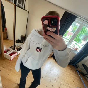 Hoodie från gantttt💘 - Säljer en vit hoodie från Gant med broderad logga och amerikanskt sköldmärke på bröstet. Tröjan har huva, magficka och långa ärmar. Klassisk och stilren design med ribbade muddar och mjukt material. Den är även jätte skön!💓