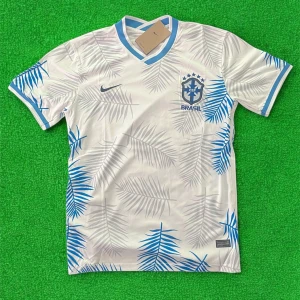 Vit Brasilien fotbollströja med blå detaljer - Snygg vit Brasilien fotbollströja från Nike med blå palmbladsmönster och blå detaljer vid krage och ärmslut. CBF-logga och Nike-märke på bröstet. Perfekt för dig som vill sticka ut på planen eller läktaren.