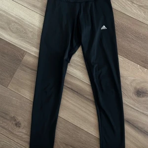 Svarta träningstights från Adidas - Svarta tights från Adidas med liten vit logga på låret. Modellen är tight. Välanvänd.