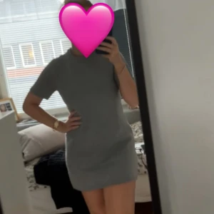 Grå stickad kortklänning - Säljer en enkel och stilren grå stickad kortklänning med rund halsringning och korta ärmar. Perfekt för en avslappnad men ändå snygg look. Passformen är normal och materialet är mjukt och bekvämt.