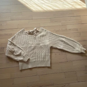 Beige stickad tröja med knyt i nacken - Säljer en beige stickad tröja med olika stickade mönster och ett fint knytband i nacken. Perfekt för lager-på-lager och snygg till både jeans och kjol.
