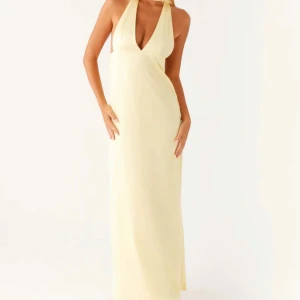 Ljusgul långklänning med djup v-ringning - Säljer en elegant ljusgul långklänning med djup v-ringning och öppen rygg. Klänningen har halterneck och långa band som knyts i nacken. Perfekt för sommarens alla tillfällen! Den är från peppermayo, säljer då den inte hann komma i tid till min bal. Såå fin klänning!