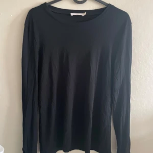 Svart långärmad tröja från Wera - En stilren svart långärmad tröja från Wera. Tröjan har en klassisk rund halsringning och är tillverkad i ett mjukt bomullsmaterial. Perfekt basplagg att ha i garderoben.