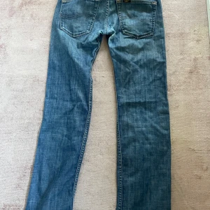 Blå raka jeans med färgfläckar - Jätte snygga lågmidjade jeans. Jeansen har unika färgfläckar i grönt, lila och rött på framsidan vilket ger dem en personlig och kreativ look. 