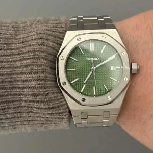 Seiko mod Royal Oak green dial  - Säljer en Seiko herrklocka med grönt mönstrat urtavla, datumvisning och silverfärgat armband i rostfritt stål. Klockan har en åttakantig boett och synlig automatisk urverk på baksidan. Perfekt accessoar för dig som gillar stilrena detaljer.