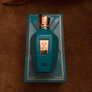 Xerjoff Erba Pura Eau de Parfum 100ml - Lyxig parfym från Xerjoff, Erba Pura, i en snygg turkosblå flaska med gulddetaljer. Flaskan rymmer 100 ml och kommer i en elegant förpackning. Doften är unisex och exklusiv, perfekt för dig som vill sticka ut med något unikt.