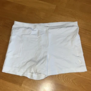 Vita träningsshorts från Adidas - Säljer ett par vita träningsshorts från Adidas med diskret logga framtill. Shortsen har elastisk midja och boll fickor på båda sidorna. Perfekta för tennis. Klassisk och enkel design. Är bara ett lager tyg. 
