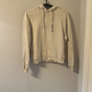 Beige hoodie från NA-KD - Säljer en enkel och stilren beige hoodie från NA-KD i storlek XS. Tröjan har huva med dragsko och långa ärmar. Perfekt för en avslappnad och bekväm stil.