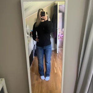 Mörkblå jeansbyxor med knappar - Säljer ett par mörkblå jeansbyxor midrise midja och är ”baggy”. Byxorna har synliga knappar framtill och klassiska fickor både fram och bak. Det blir ljusare vid knäna super fina! 