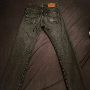 Levis 501 svarta jeans - Klassiska svarta Levis 501 jeans med raka ben och femficksmodell. Jeansen har knappgylf och den ikoniska Levis-lappen bak i midjan. Passar perfekt till en avslappnad stil och är ett måste i garderoben. JÄTTE BRA SKICK OCH SNABB LEVERANS. Dm vi funderingar eller frågor