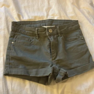 Gröna jeansshorts från H&M - Tyvärr för små men inte jättemycket använda och bra skick. Snygga gröna jeansshorts från H&M med klassisk femficksdesign och uppvikta benslut. Perfekta för sommaren och enkla att matcha med olika toppar. Stängs med knapp och dragkedja.