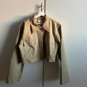 Beige croppad jacka från H&M - oanvänd - Snygg croppad overshirt från H&M. Storlek L. Köpt för 699, säljer för endast 450kr. Kom med prisförslag. 