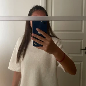 Vit stickad kortärmad tröja Gina Tricot - Superfin vit stickad tröja från Gina Tricot med korta ärmar och rund hals. Tröjan har en loose passform och ribbade kanter vid ärmslut och nederkant. Perfekt att styla med jeans eller kjol för en clean look. tröjan är endast använd ett få tal gånger därför är den i nytt skick. Storlek Xs men passar även dig som bär S