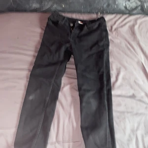 Svarta slim fit jeans från H&M - Svarta jeans från H&M i slim fit-modell med justerbar midja. Klassisk femficksdesign, dragkedja och knapp framtill. Jeansen är i stretchigt material som sitter snyggt och bekvämt. Perfekta för dig som gillar en stilren och enkel look.