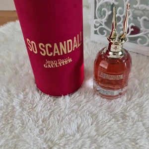 Scandal Jean Paul Gaultier parfym - So Scandal från Jean Paul Gaultier, 80 ml Eau de Parfum. Flaskan är genomskinlig med rosa doftvätska och har en unik guldfärgad kork formad som ben. Kommer i en lyxig mörkrosa cylinderförpackning med guldtext.