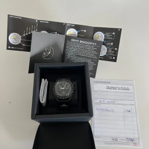 Omega x Swatch MoonSwatch Speedmaster - Säljer en svart Omega x Swatch MoonSwatch Speedmaster med tydlig tachymeter-skala och flera subdials. Klockan har en rund boett, svart armband och vita detaljer på urtavlan. Perfekt för dig som gillar rymdtema och snygg design. Levereras i originalbox med manual.