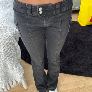 Svarta bootcut jeans från H&M - Säljer ett par svarta bootcut jeans från H&M med låg midja och justerbar midja. Jeansen har cargofickor på sidorna, snygg tvätt och stretchigt material som sitter skönt. Jeansen är nerlagda då dom är för korta för mig! 💐☀️