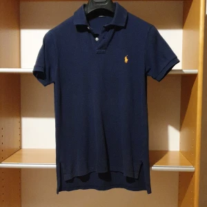 Marinblå pikétröja från Ralph Lauren - Snygg marinblå pikétröja från Ralph Lauren i passform custom fit.