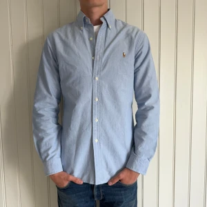 Ralph Lauren skjorta - En ljusblå Ralph Lauren skjorta slim fit som passar perfekt till sommaren. Storleken är M. Skicket är 9,5/10 då det inte syns att den är använd. Vid frågor och funderingar är det bara höra av sig. Priset går självklar att diskuteras🤗