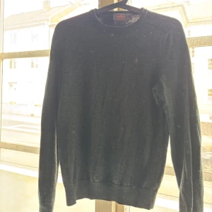 Merino Stickad Morris - Klassisk mörkgrön stickad tröja från Morris med rund halsringning och diskret broderad logga på bröstet. Tröjan är 100% merino wool