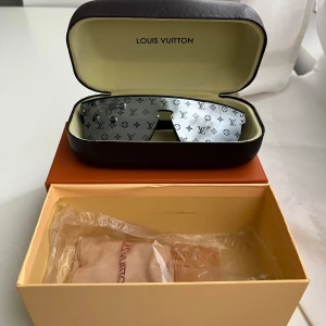 Louis Vuitton monogram solglasögon - Snygga solglasögon från Louis Vuitton med spegelglas och ikoniskt LV-monogram över hela linsen. Sköldformad design med silvriga detaljer, levereras i originaletui och box. Perfekt accessoar för dig som vill sticka ut och visa stil.
