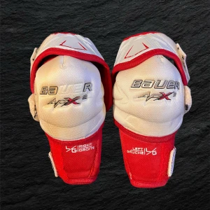 Bauer APX2 armbågsskydd  - Säljer ett par Bauer Vapor APX2 armbågsskydd i storlek Jr-L. De är vita och röda med justerbara kardborreband och extra skydd runt armbågen. Perfekta för hockey. Snygg design och bra passform för dig som vill ha grymt skydd på isen.