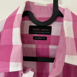 Rutig rosa skjorta från Zara Man - Snygg rutig skjorta från Zara Man i rosa och vitt. Skjortan har två bröstfickor med lock och knappar, klassisk krage och lång ärm. Skräddarsydd passform som sitter riktigt bra. Perfekt för dig som vill sticka ut med färg och mönster.