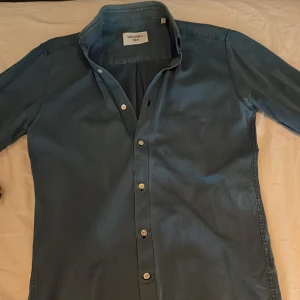 Blå skjorta från Our Legacy strl S - Säljer en stilren blå skjorta från Our Legacy i storlek S. Skjortan har klassisk krage, långa ärmar och vita knappar framtill. Materialet känns mjukt och lätt, perfekt för dig som gillar minimalistisk och clean stil.