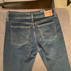 Blå jeans från Levi's - Snygga blå jeans från Levi's med klassisk femficksdesign och låg midja. Modellen är Superlow Boot, vilket ger en skön passform med lite utsvängda ben. Perfekta för en avslappnad stil.