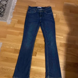 Blå bootcut jeans från Zara! Perfekt skick!  - Snygga blå bootcut jeans från Zara med klassisk femficksdesign. De har en lågmidjad passform och är perfekta för en avslappnad stil. Jeansen har en dragkedja och knapp framtill. Lågmidjade! 