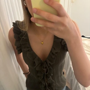 Grön ribbad topp med volangdetaljer - Snygg grön ribbad topp med volangdetaljer och knyt framtill. Toppen är ärmlös och har en v-ringad design❣️❣️❣️så fin!! Använd fåtal gånger 