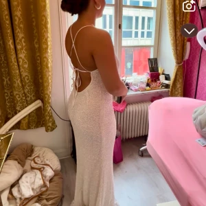 Balklänning - Jag säljer min gamla balklänning från Bubbleroom. Använd 1 gång och är i storlek M. Den är vit med glittriga paljetter. Lite smutsig nertill då det regnade. Den går att handtvätta eller sy upp då den är väldigt lång för mig både med och utan klackar (är 165cm🩷) Jag är villig att förhandla om priset. Ordinarie pris 1599kr