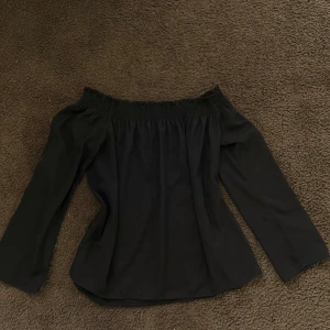Svart offshoulder topp - Snygg svart offshoulder topp med långa ärmar. Perfekt för en stilren look. Toppen har en elastisk kant vid axlarna för en bekväm passform. Passar till alla tillfällen!🌸🌸