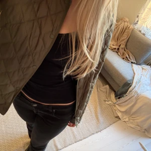 Olivgrön quiltad jacka - Säljer en olivgrön quiltad jacka med knappar. Jackan har en normal passform och är perfekt för höst och vår. Den är långärmad och har en stilren design som passar till många olika outfits.