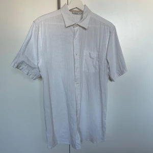 Vit kortärmad skjorta från Livergy - Säljer en stilren vit kortärmad skjorta från Livergy. Skjortan har en klassisk krage och knappar framtill. Perfekt för varma dagar eller sommarens tillställningar.