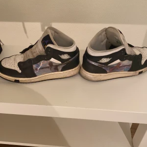 Nike Air Jordans i svart och vit - Säljer ett par klassiska Nike Air Jordans i svart och vit. Skorna har en ikonisk design med snörning och en broderad logga på sidan. Perfekta för dig som älskar sneakers med stil. Extra skosnören i lila medföljer. Dom e ganska smutsiga därför kommer ja sälja dom för lågt pris äkta ett tag g