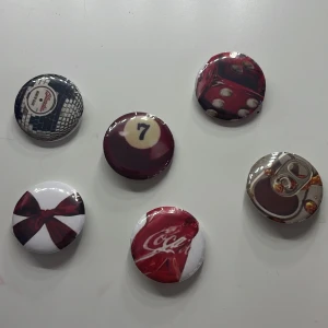  pins - Säljer pins för 8 kr styck med retroinspirerade motiv. Motiven inkluderar en biljardboll, en Coca-Cola flaska, en röd tärning, en rosett och en läskburksöppnare. Perfekt för att ge din outfit en personlig touch!