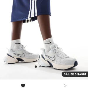 Vita sneakers från Nike - Snygga vita sneakers från Nike med en stilren design och mörkblå detaljer. Skorna har en bekväm sula och klassisk snörning, perfekt för både träning och vardag. Använda en gång, säljer då dom är för små skulle behöva en 39 1/2