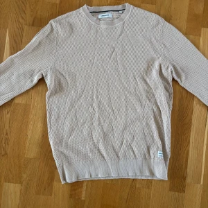 Beige tröja från Jack&Jones - Säljer en stilren beige tröja från Jack&Jones med ett diskret mönster. Tröjan har långa ärmar och rund halsringning. Perfekt för en avslappnad look. Jag säljer denna för att den inte riktigt är min stil och kommer aldrig till användning. Tröjan är i väldigt fint skick☺️ Tröjan är i storlek L.