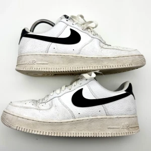 Vita Nike Air Force One sneakers - Säljer ett par klassiska vita Nike Air Force sneakers med svart swoosh. Skorna har snörning och en rund tå. Perfekta för en stilren look och passar till nästan allt! Helt okej använda, fortfarande i väldigt bra skick! Nypris runt 1499kr, vad jag kan se på Nikes hemsida. 