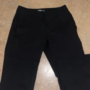 Svarta byxor från BikBok - Snygga svarta byxor från BikBok i en klassisk design. De har en rak passform och är perfekta för en stilren look. Byxorna har hällor för bälte och diskreta fickor baktill.