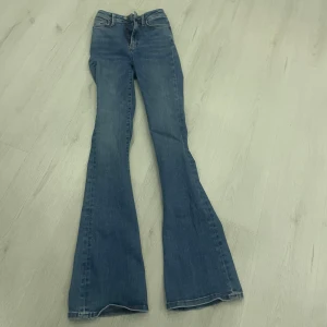 Blå bootcut jeans - Snygga blå bootcut jeans med hög midja. Perfekta för en avslappnad stil med en touch av retro. De har en klassisk femficksdesign och dragkedja med knapp framtill.