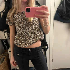 Leopardmönstrad blus - Säljer en trendig leopardmönstrad blus med korta ärmar och volangdetaljer. Perfekt för att ge din outfit en vild touch. Blusen har en bekväm passform och är lätt att matcha med olika stilar.