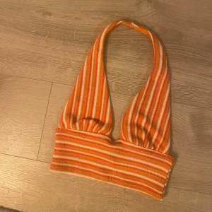 Randig halterneck topp  - Randig halterneck topp i orange och vit. Toppen har en croppad design och öppen rygg. Ingen prislapp kvar men helt oanvänd. 
