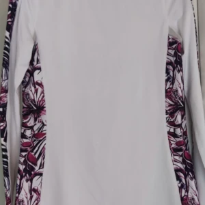 Vit långärmad tröja från Stronger - Säljer en vit långärmad tröja från Stronger med blommigt mönster i lila och svart längs ärmarna. Perfekt för en stilren och sportig look. 🌸